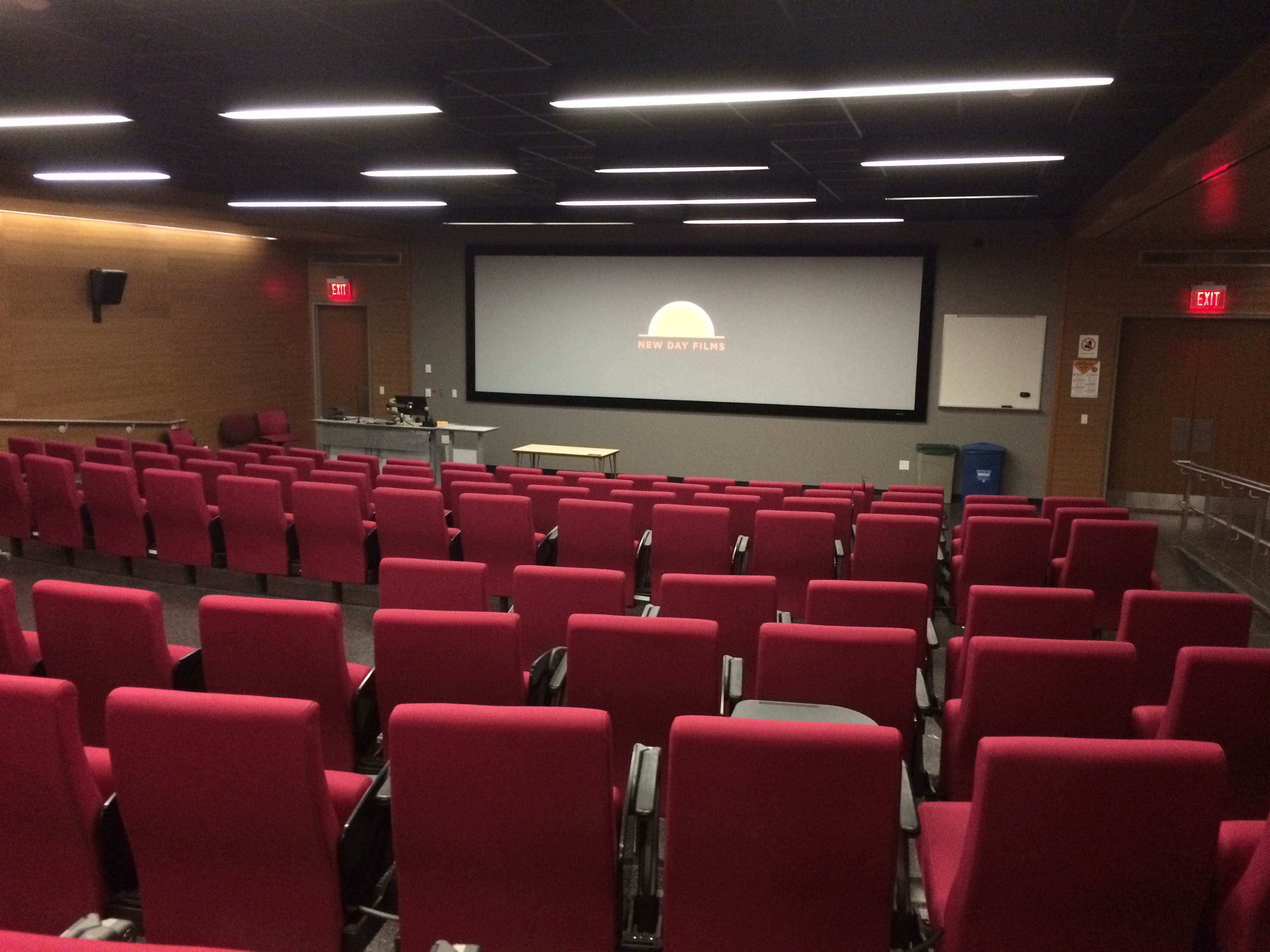 Large empty lecture hall with a screen in front. A sunset is displayed.