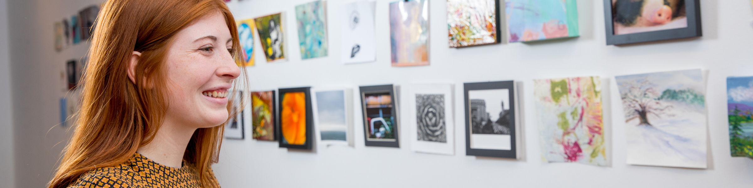 Woman looking at small paintings mounted on wall