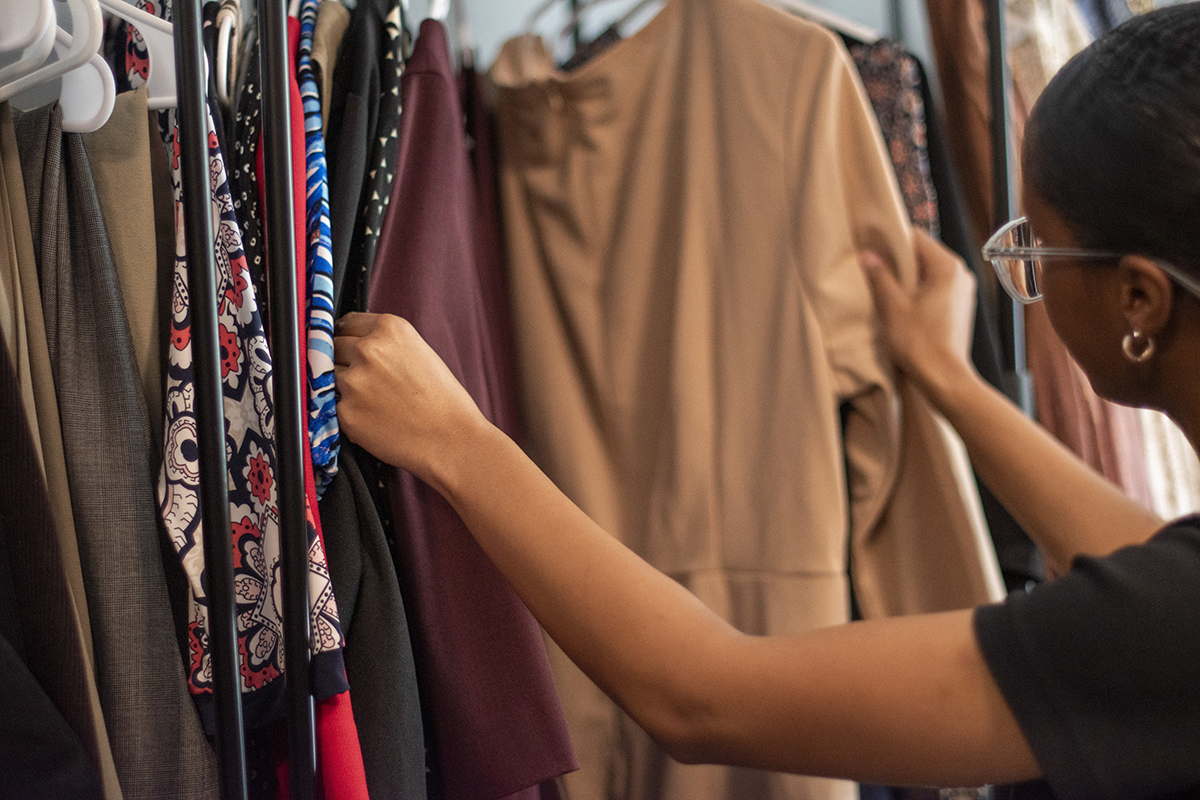 Student browsing through clothes on hangars