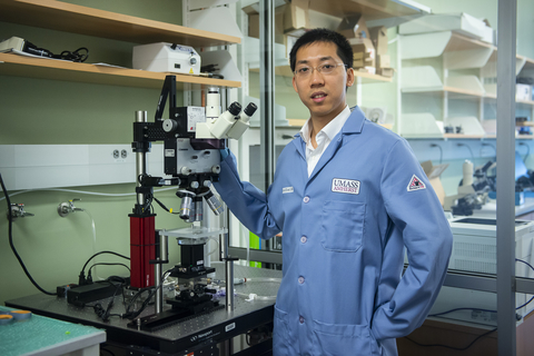 Leo Liu in front of microscope in lab